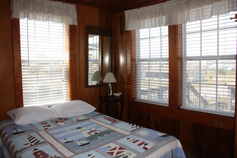Corner bedroom with wraparound windows and a lighthouse quilt