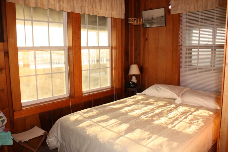 Oceanfront bedroom in warm evening light with pier views