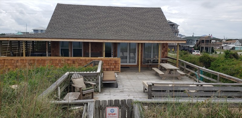 Oceanfront deck with picnic tables and loungers behind the dune