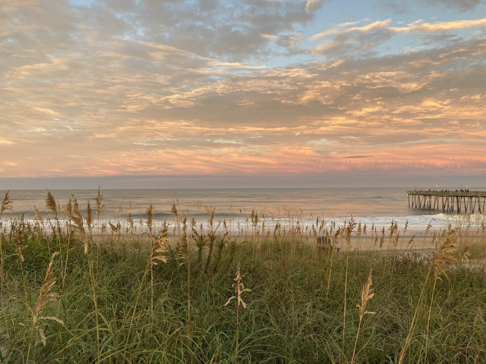 Sunset over the Atlantic from the dunes at Snooze Landing, with sea oats in the foreground and Avalon Pier in the distance