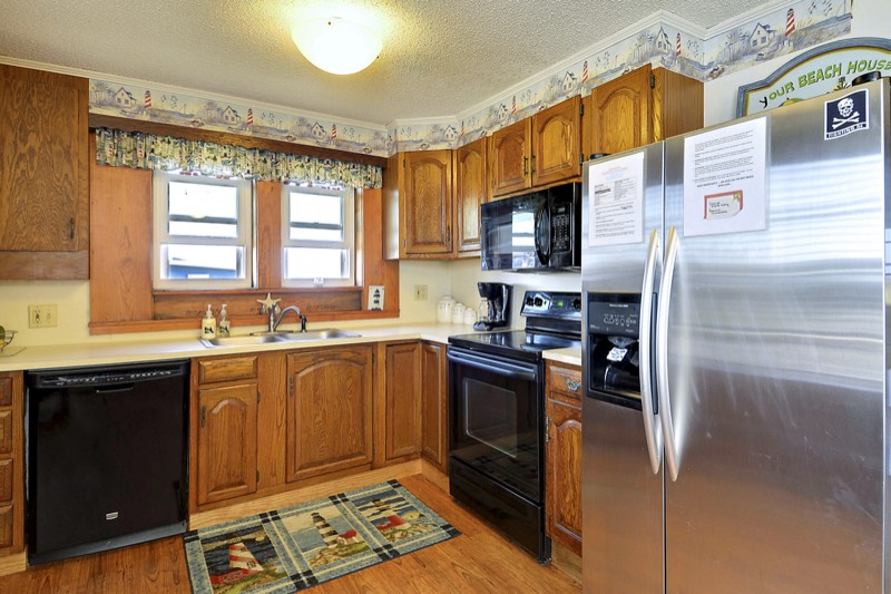 Kitchen with oak cabinets, stainless fridge, and lighthouse decor